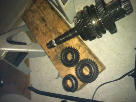 1993 Ford Probe - Transmission input shaft and gears laid out on a wooden block, possibly for repair or inspection.