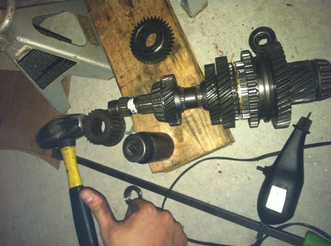 1993 Ford Probe - Disassembled transmission gears and associated tools, including a hammer and jack stand, are laid out on a concrete surface.