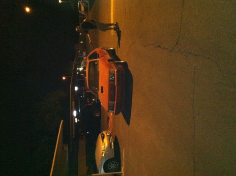 1993 Ford Probe - An orange sports car is parked on the street at night, with a person standing next to it.