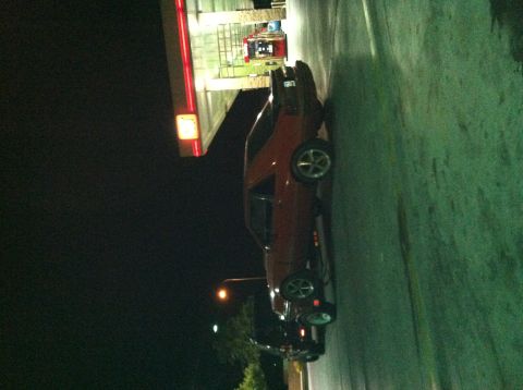 1993 Ford Probe - A red coupe is parked at a gas station at night.