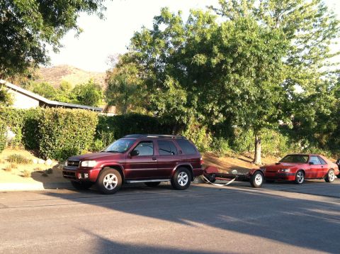 1993 Ford Probe - Red 1987 Ford Mustang GT coupe is seen from a 3/4 front view, towing a trailer.