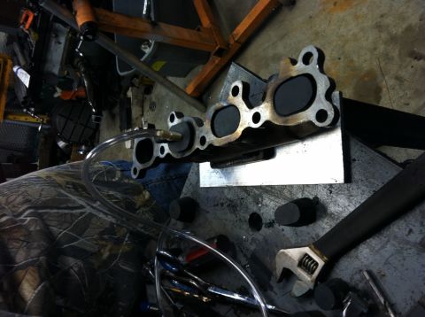 1993 Ford Probe - A close-up view of an exhaust manifold with a tube connected, suggesting a test or cleaning process.