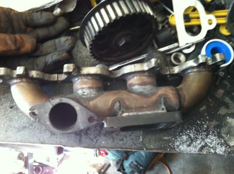 1993 Ford Probe - Close-up of an exhaust manifold and a timing gear, likely in a workshop setting.