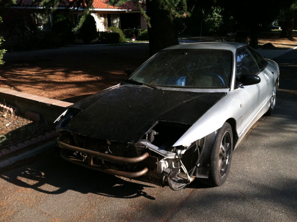Silver 1993 Ford Probe with black hood and damaged front end
