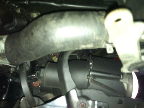 1993 Ford Probe - A close-up view of engine components, including a thick hose and the starter motor assembly.