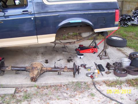 1990 Ford Bronco - A 1990 Ford Bronco is undergoing rear axle maintenance, with tools and parts laid out on the ground.