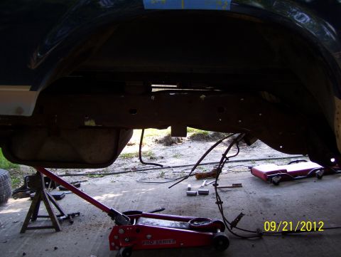 1990 Ford Bronco - Working on the undercarriage of a vehicle, with the fuel tank lowered.