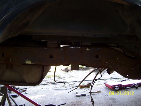 1990 Ford Bronco - The vehicle's frame and fuel tank are visible, with tools scattered on the ground below.