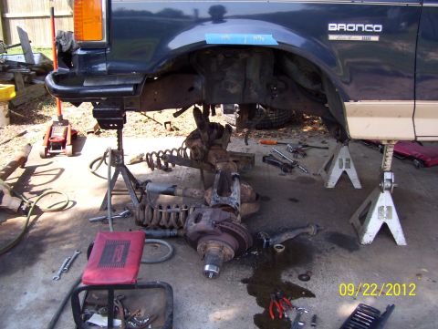 1990 Ford Bronco - Front suspension of a 1990 Ford Bronco undergoing repairs, supported by jack stands.