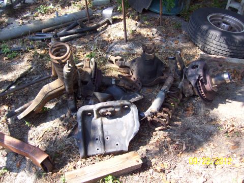 1990 Ford Bronco - Various disassembled vehicle components are scattered on the ground, suggesting a project or repair.