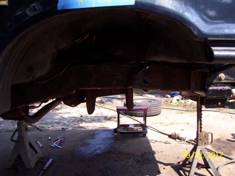 1990 Ford Bronco - Undercarriage of a vehicle undergoing maintenance, with tools scattered nearby.