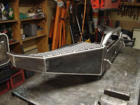1989 Ford Bronco - A custom-fabricated winch bumper with a diamond plate top sits on a workbench.