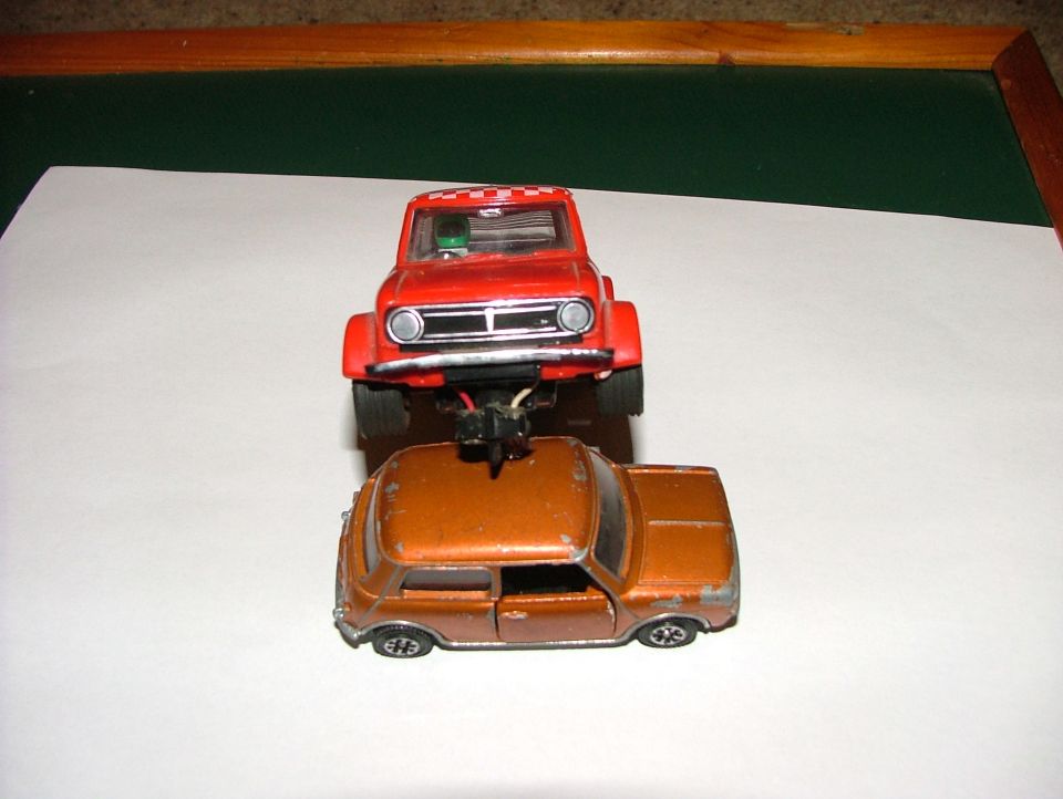 Two toy cars, one red on top of an orange one