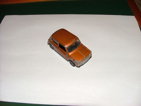 1980 MINI Cooper - A small orange toy car is photographed from a three-quarter front angle on a white background.
