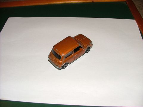 1980 MINI Cooper - A small orange toy car is shown from a 3/4 front angle on a white surface.