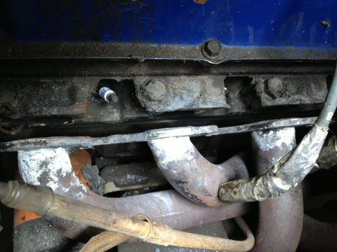 1979 Ford F-350 - A close-up view of an engine's spark plug and exhaust manifold components.