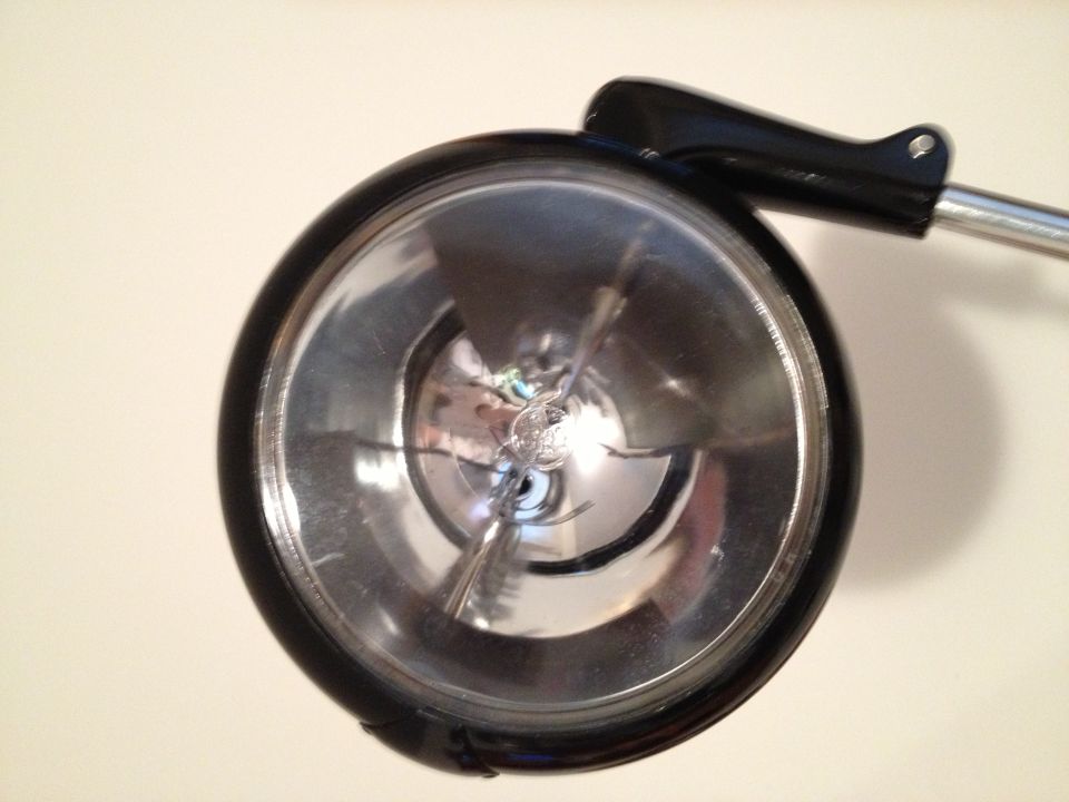 Close-up of a round headlight assembly with a black housing and chrome reflector