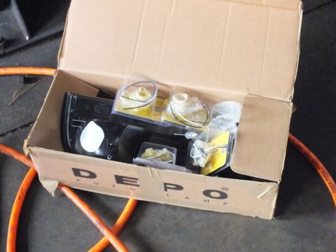 2003 Ford Crown Victoria - DEPO-branded box holding a replacement headlight assembly and bulb hardware on shop floor.