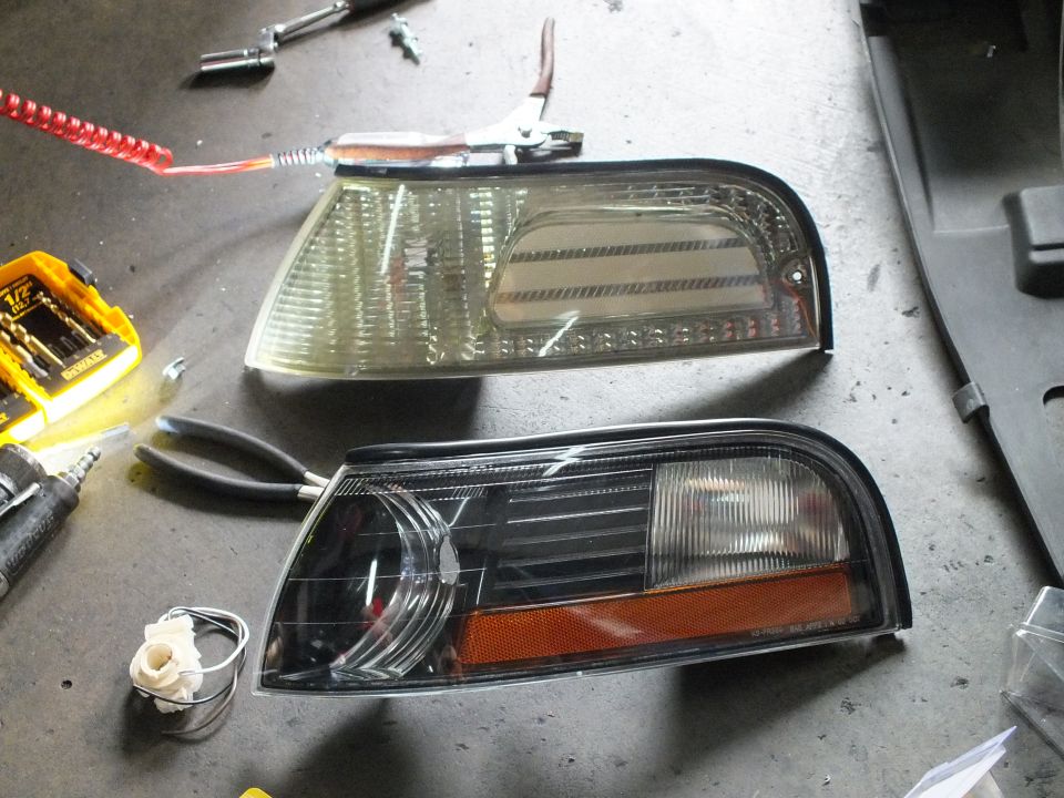 Two corner marker lights on shop floor, clear-lens unit above black housing with amber reflector