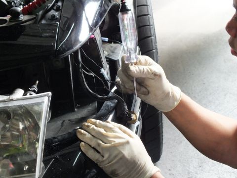 2003 Ford Crown Victoria - Hands in latex gloves probe front-end wiring with a test light during electrical work on a black vehicle