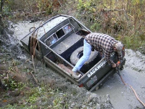 1988 Ford Bronco - A 1988 Ford Bronco is stuck in the mud, with a person attempting to pull it out.