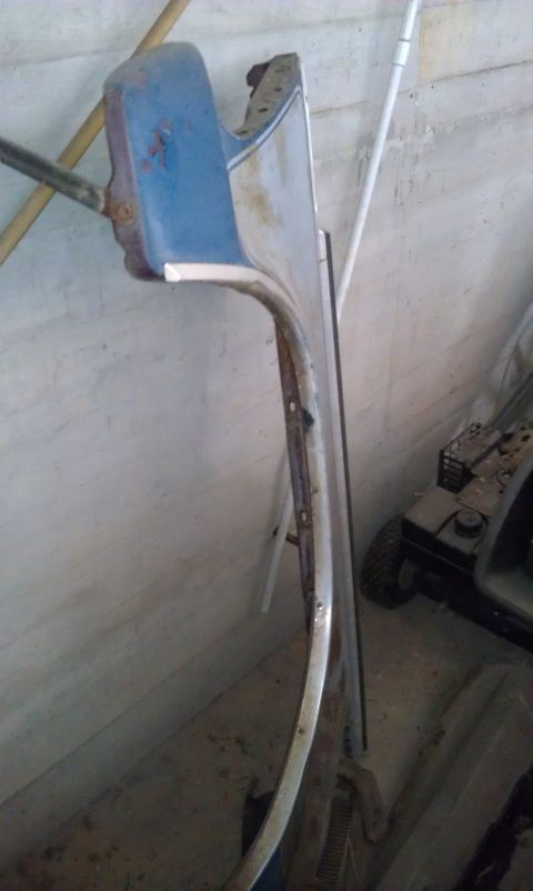 1974 Oldsmobile 442 - A blue and chrome car fender is stored indoors, leaning against a wall.