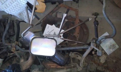 1974 Oldsmobile 442 - Assorted car parts piled up, including a side mirror and brake components.