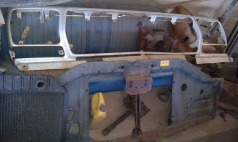 1974 Oldsmobile 442 - Disassembled car front end parts, including a grille and radiator support, are laid out.