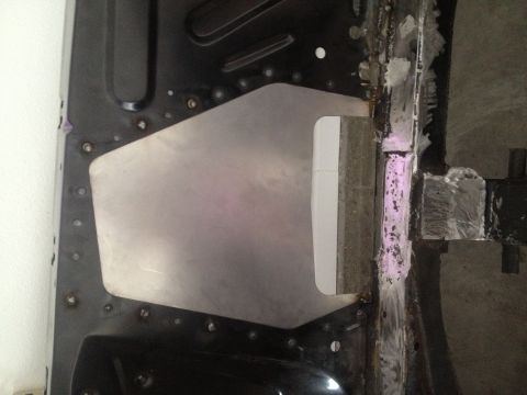 1965 Ford Mustang - Repair work on a vehicle's interior floor pan shows a metal patch being applied with sealant.