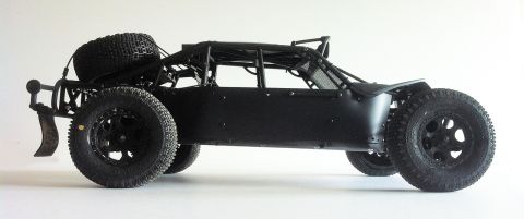 1986 Ford Bronco - Side view of a black off-road buggy with a roll cage and spare tire.