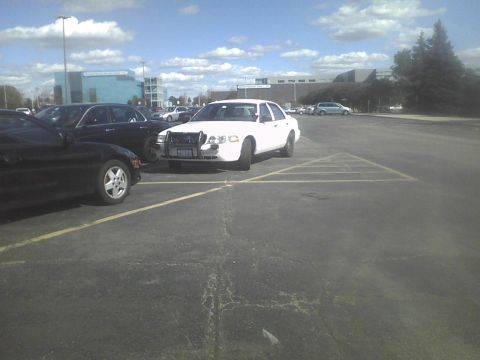 2003 Ford Crown Victoria - White 2003 Ford Crown Victoria police car with push bumper parked in a lot.