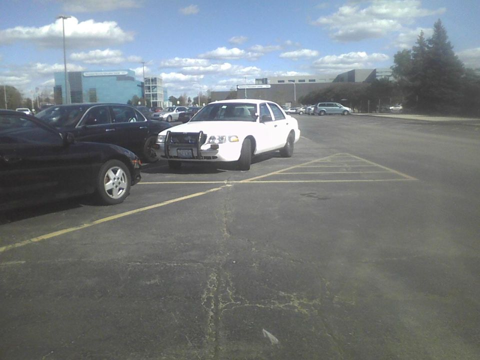 2003 Ford Crown Victoria police car parked in lot, front view. Black car to the left