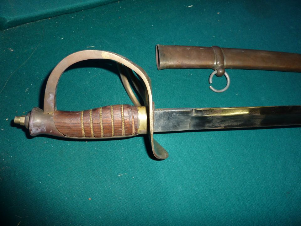 Sword with wooden handle and brass guard, next to a brass scabbard with a ring