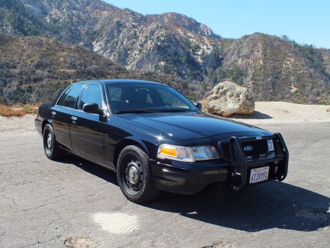 2003 Ford Crown Victoria - Front three-quarter view of a black Crown Victoria Police Interceptor with steel wheels and push bar on a turnout.