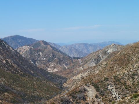 2003 Ford Crown Victoria - V-shaped canyon descends between brushy ridges toward layered hazy ranges in the distance.