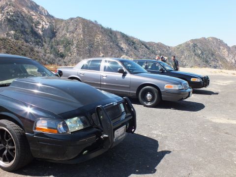 2003 Ford Crown Victoria - Front three-quarter of a black sedan with grille guard among parked cars and people behind