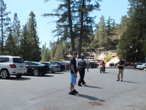 2003 Ford Crown Victoria - Men walk across a paved mountain lot lined with cars and SUVs as motorcycles gather behind