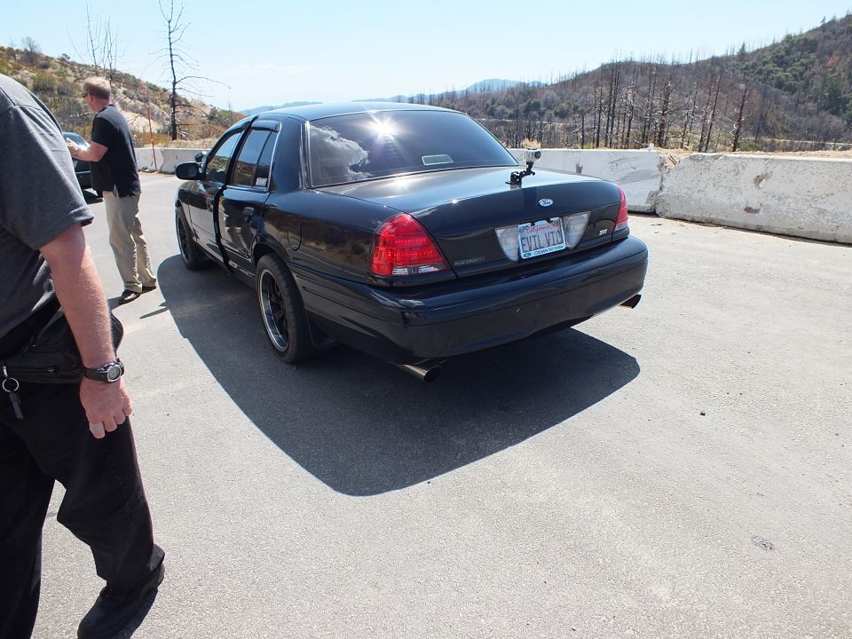 Rear three-quarter view of black Ford Crown Victoria with EVIL VIC license plate