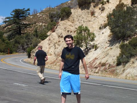 2003 Ford Crown Victoria - Man poses on the road as a second person walks toward a curve below the hillside.