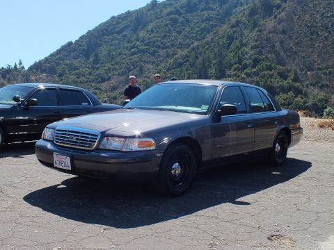 2003 Ford Crown Victoria - Front three-quarter of a gray full-size Ford sedan with black steel wheels, plate 6THE1AA