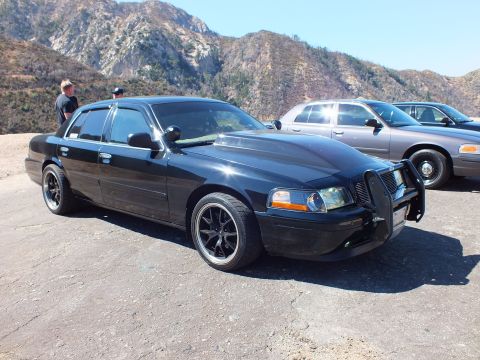 2003 Ford Crown Victoria - Lowered black Mercury sedan with waterfall grille and push bar beside a gray Ford sedan