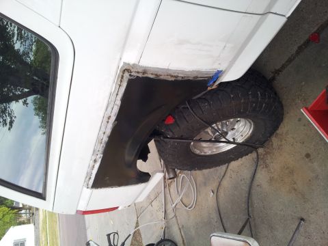1996 Ford Bronco - Welding repair on a white SUV's rear fender panel, showing a large off-road tire.