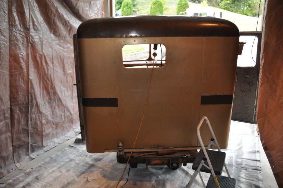 Truck sleeper cab, tan with dark brown top, inside a garage with tarps