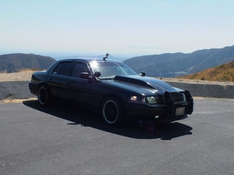 2003 Ford Crown Victoria - Murdered-out Crown Vic sedan with grille guard parked at a mountain pullout