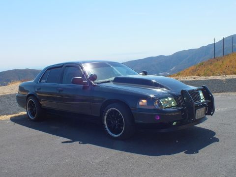 2003 Ford Crown Victoria - Front-three-quarter of a murdered-out police-style sedan on a paved overlook