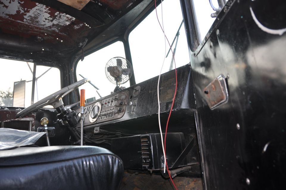 Interior of a truck cab, showing the dashboard, steering wheel, and a fan