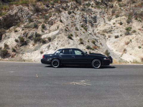 2003 Ford Crown Victoria - Side view of a lowered black Mercury Grand Marquis parked before a rocky road cut.