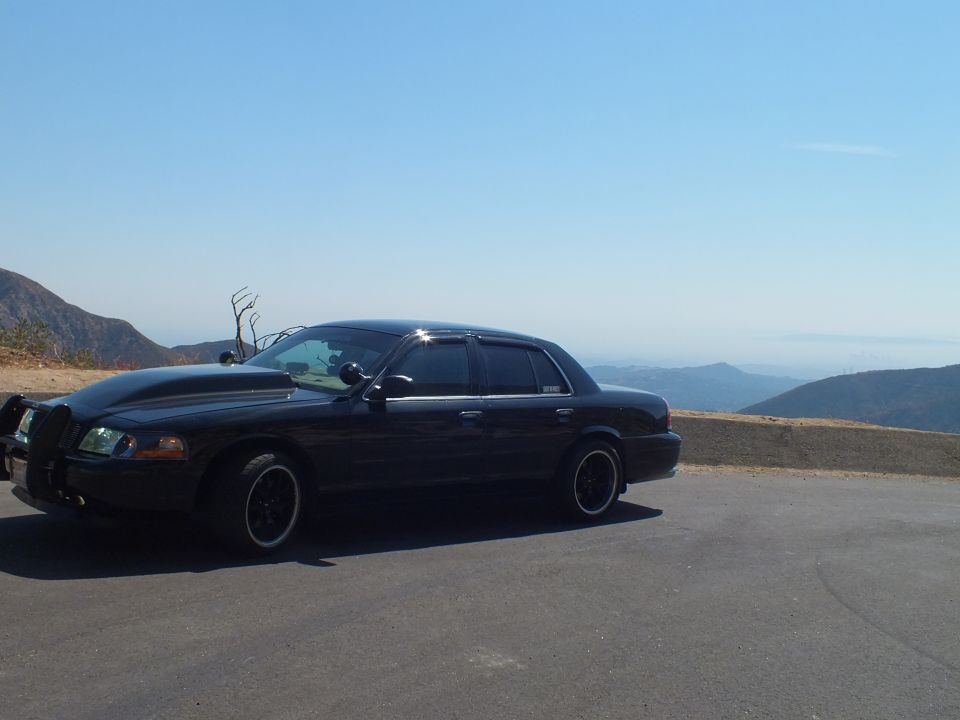 Black Mercury Grand Marquis side profile at hilltop overlook with valley view
