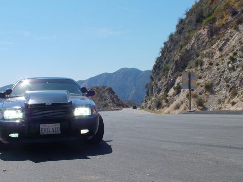 2003 Ford Crown Victoria - Blacked-out Crown Vic at a roadside turnout with mountains and a trail sign across the valley.