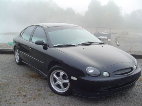 1999 Ford Taurus - A black 1999 Ford Taurus is parked outdoors on a foggy day.